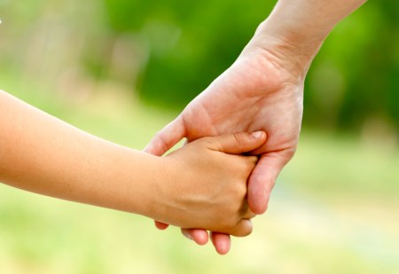 Mother holds the hand of her child